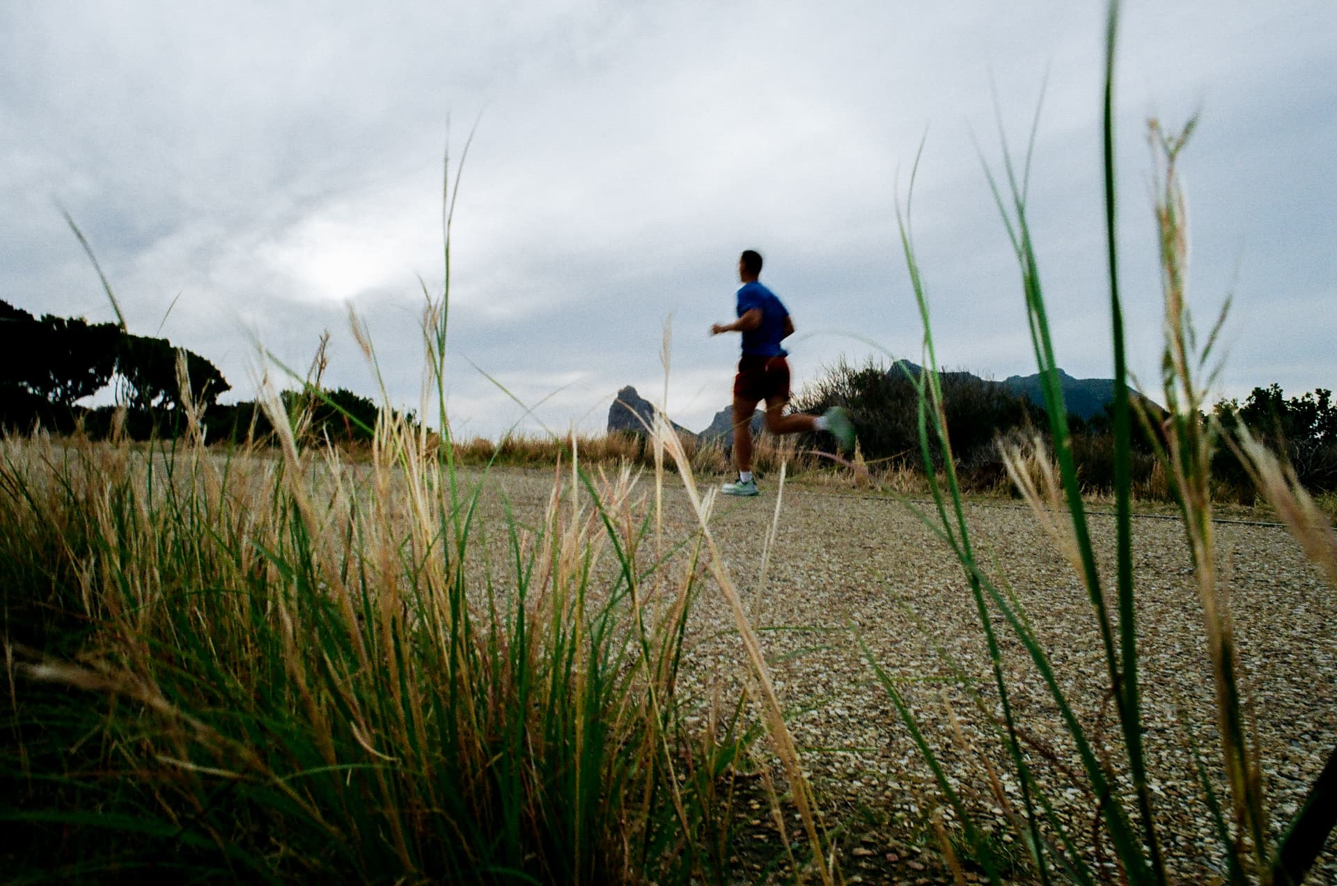 Runner on a gravel path with mountains behind